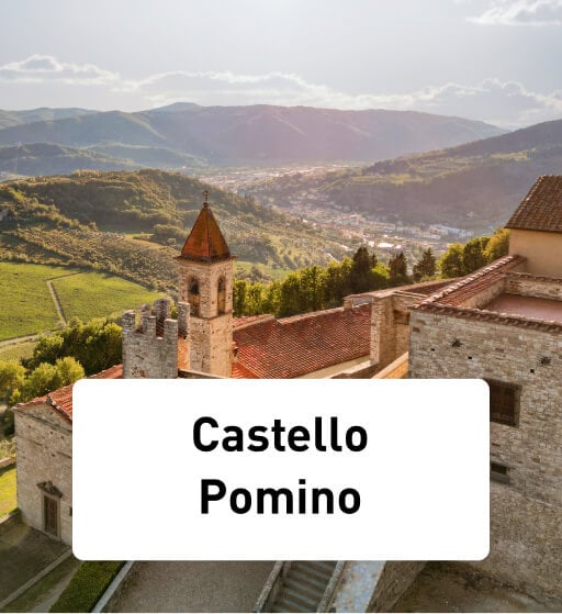 Castello Pomino: plaatje van het kasteel van bovenaf genomen, waarbij je op de achtergrond allemaal bergen en wijngaarden ziet